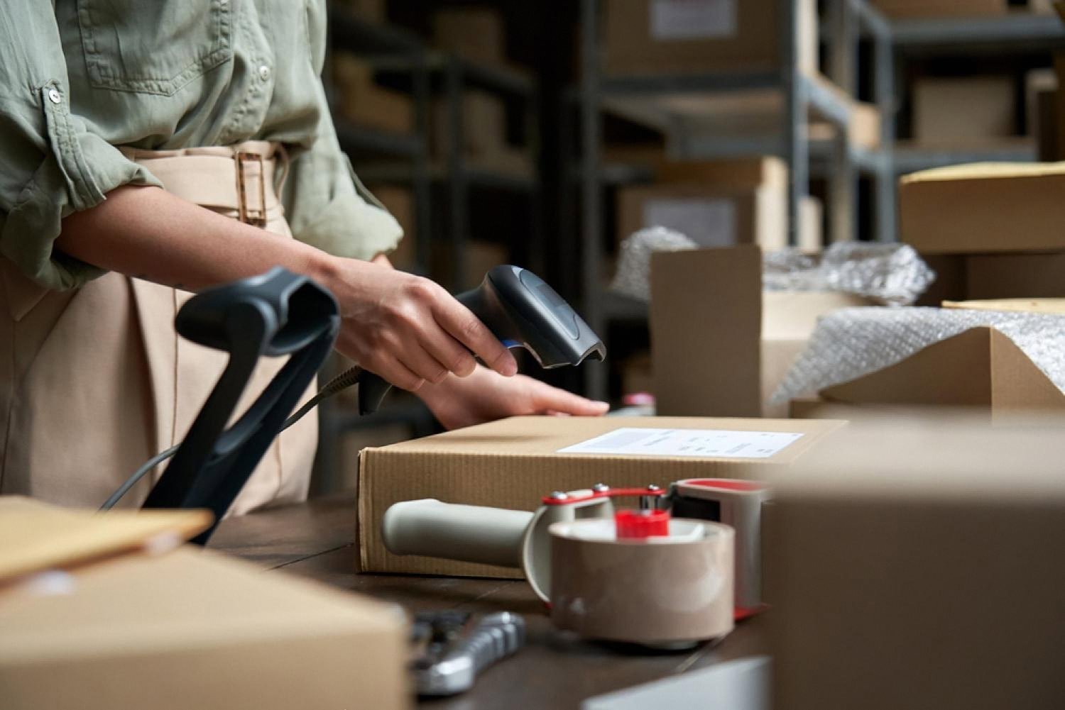 Warehouse worker scanning a boxed rental item ready for dispatch to a customer